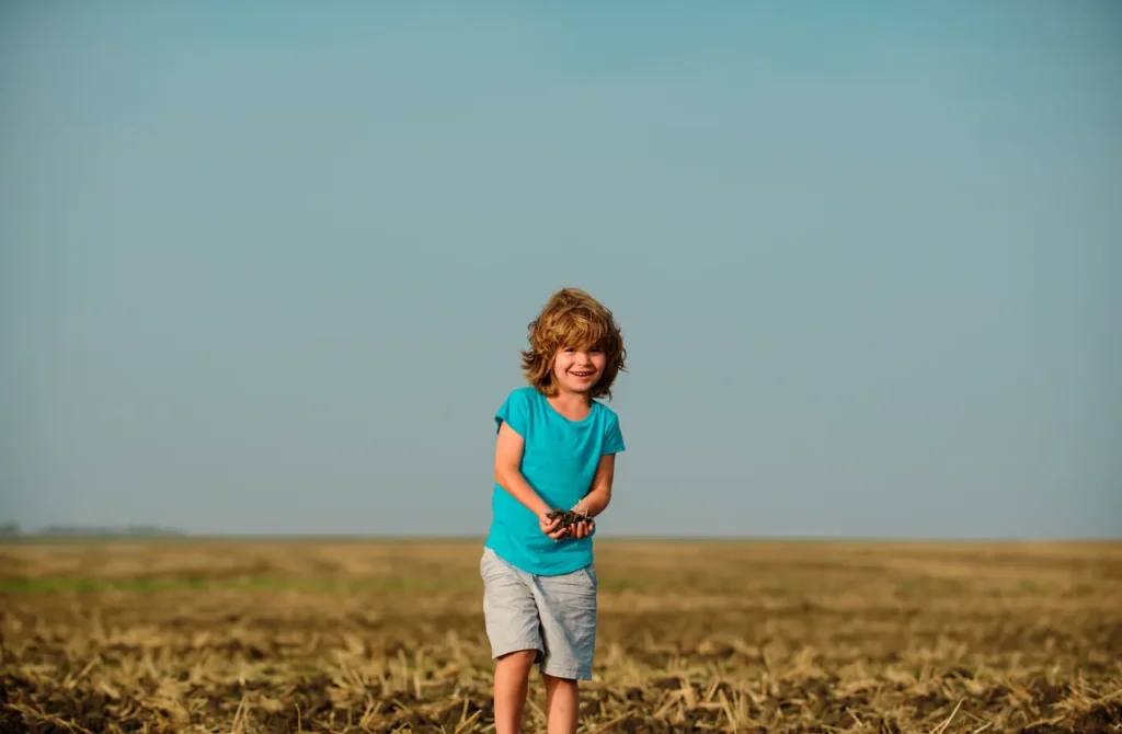 Child Playing With Dirt In A Field